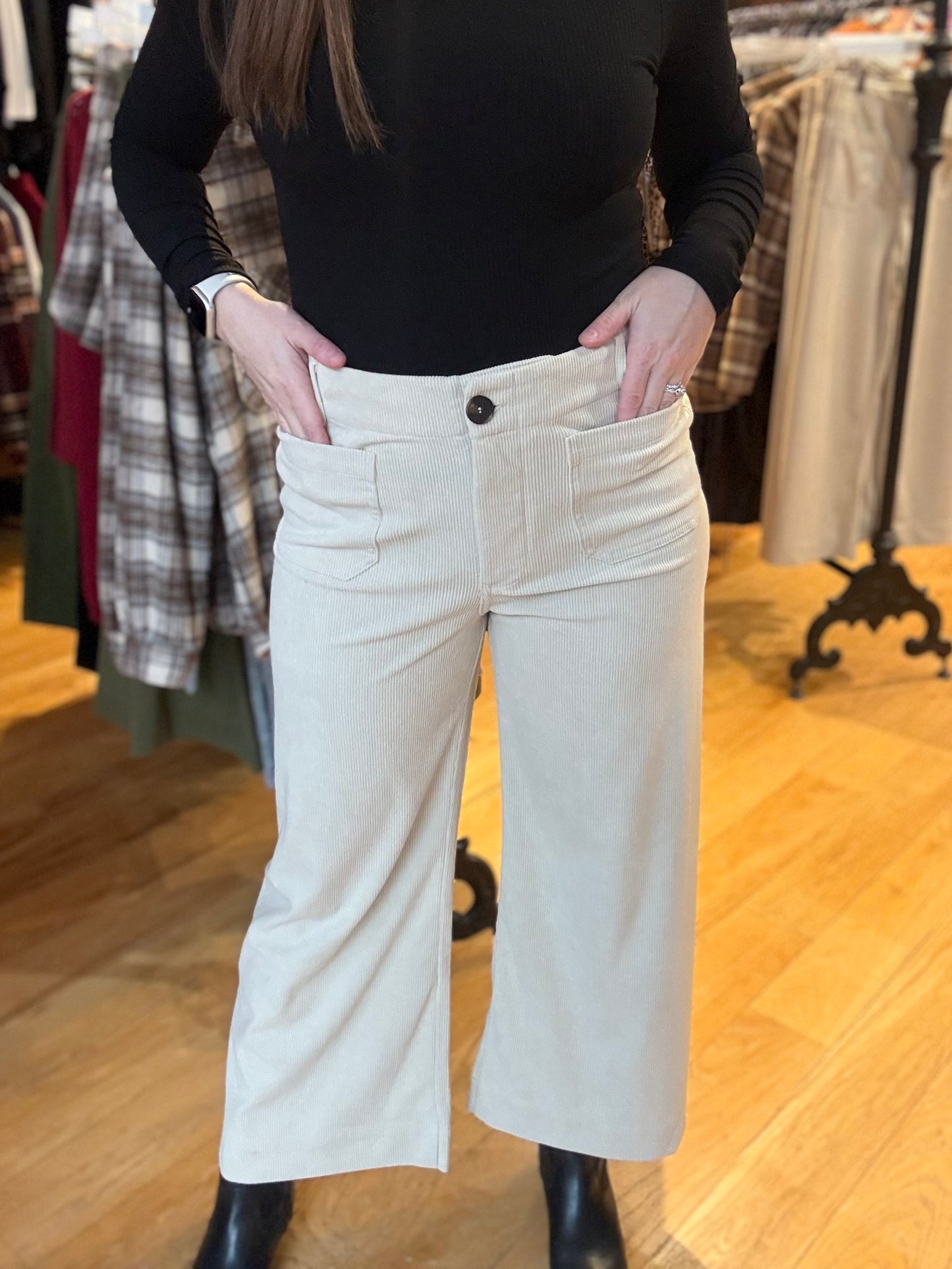 Person wearing a black top and beige wide-leg pants in a clothing store.