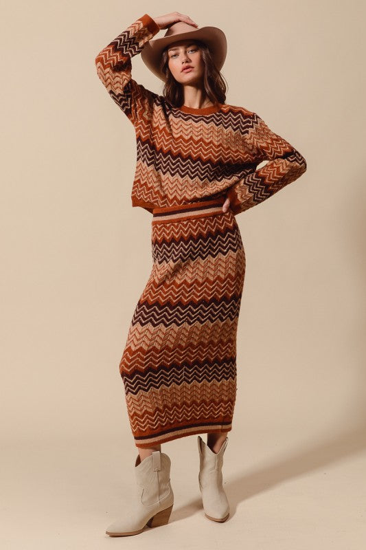 Woman wearing a patterned sweater and skirt set with white boots on a beige background