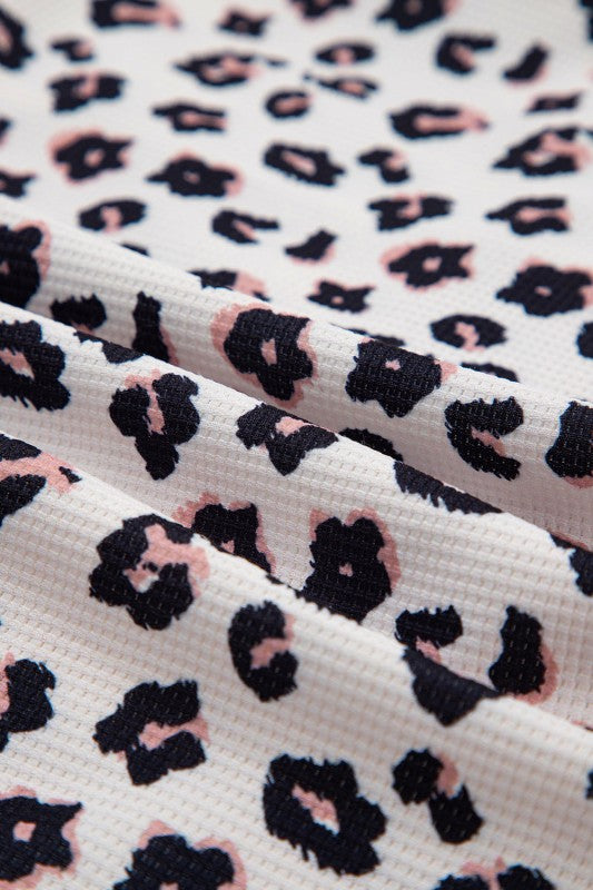 Close-up of fabric with black and pink leopard print pattern on a white background