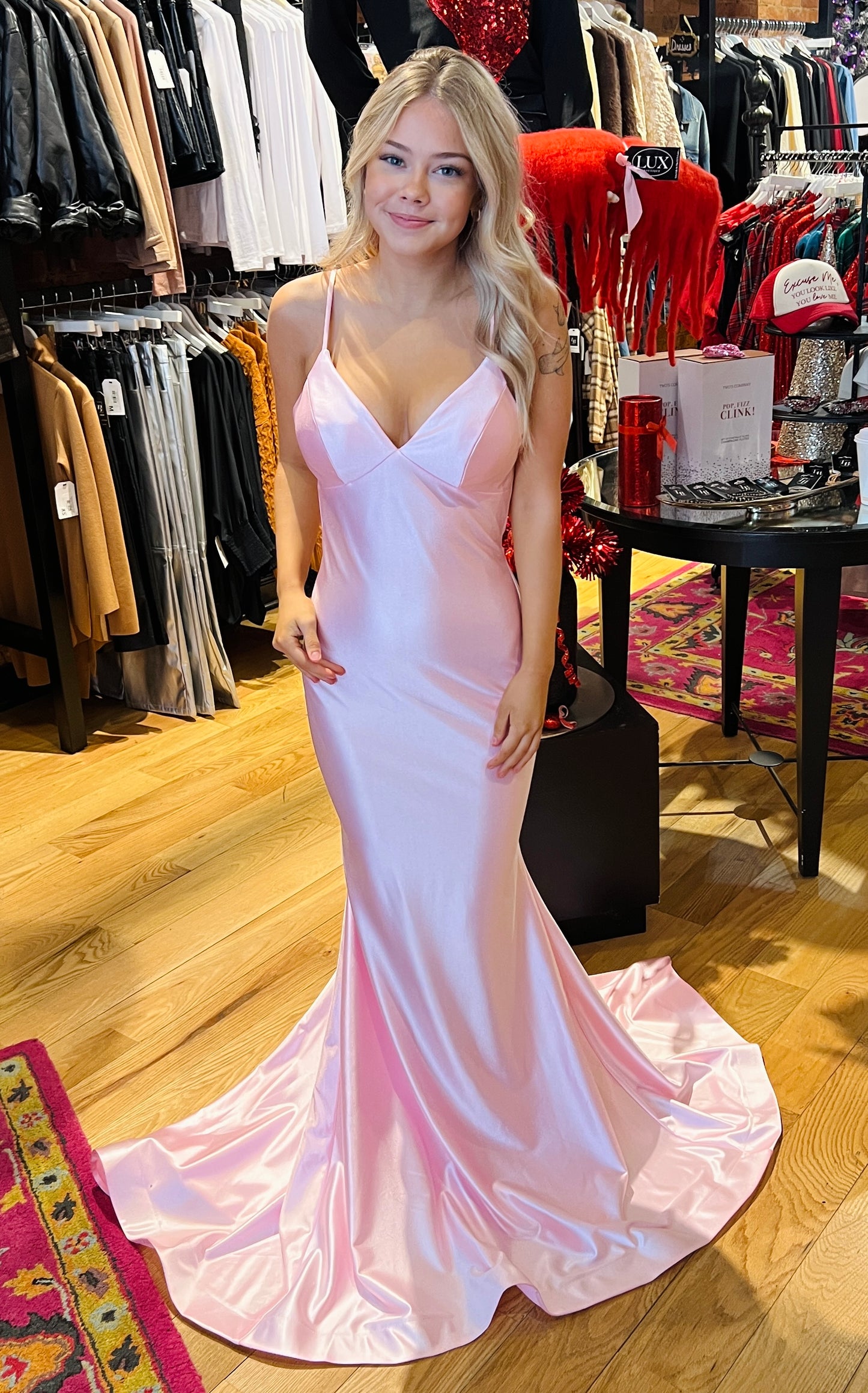 Woman in a pink evening gown standing in a clothing store.