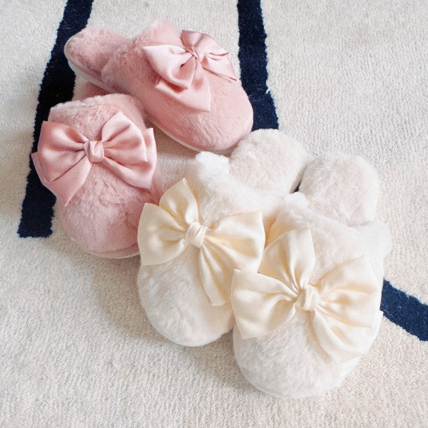 Pink and white slippers with large bows on a light background