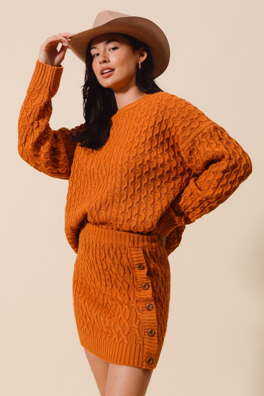 Woman wearing an orange knitted dress and hat against a beige background