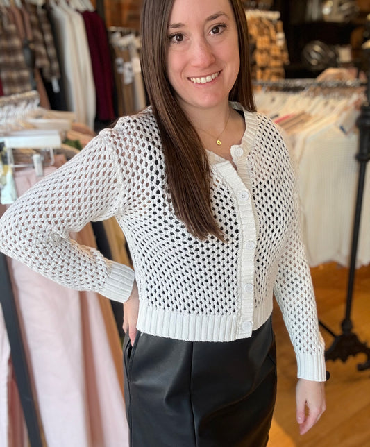 Woman wearing a white textured cardigan in a clothing store.