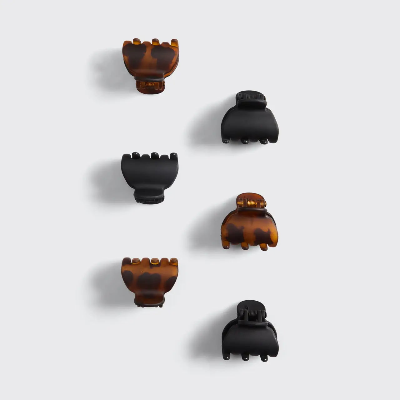 Set of tortoiseshell and black hair clips on a light gray background
