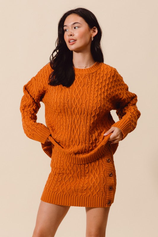 Woman wearing an orange knitted sweater dress against a beige background