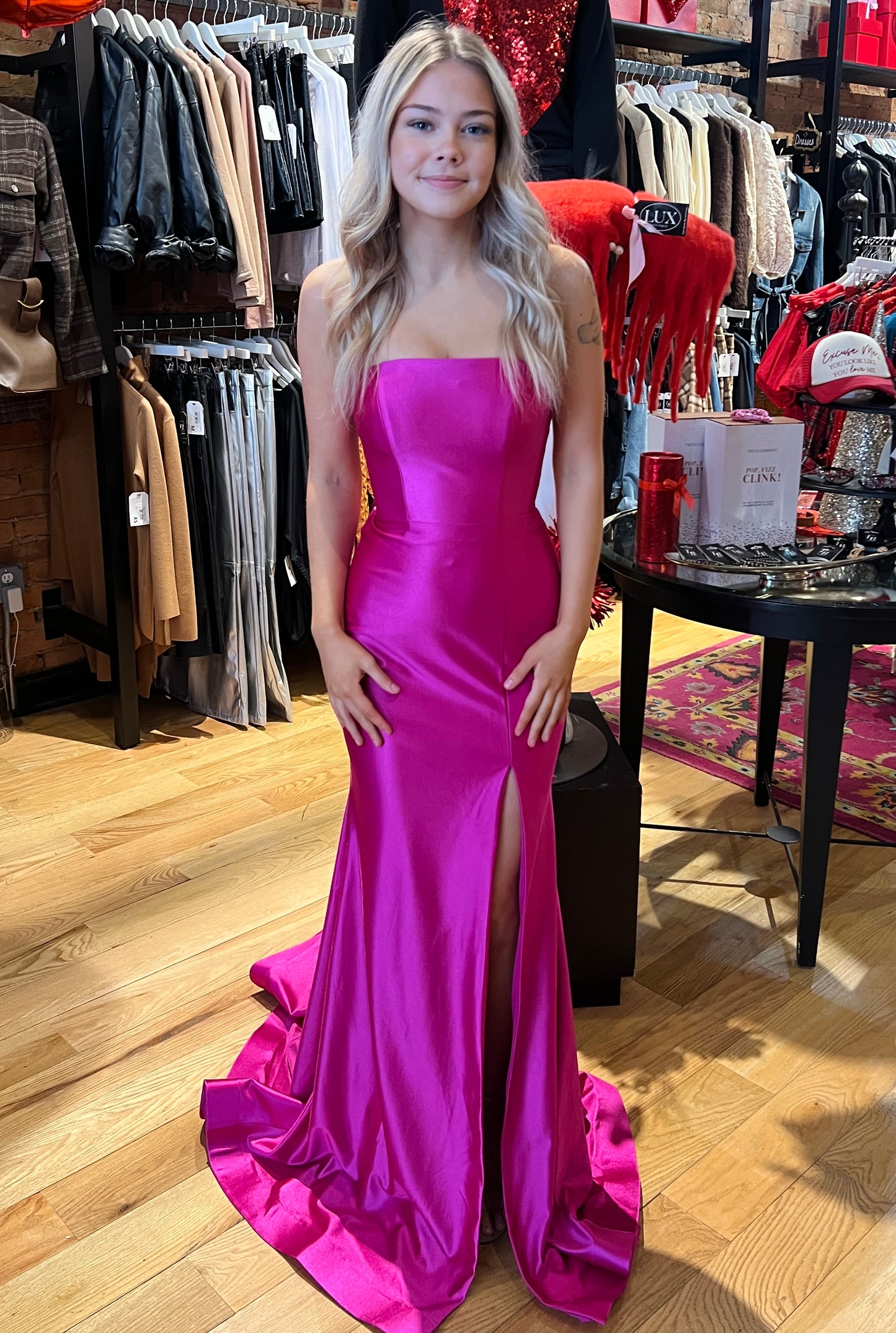 Woman in a pink strapless gown standing in a clothing store.