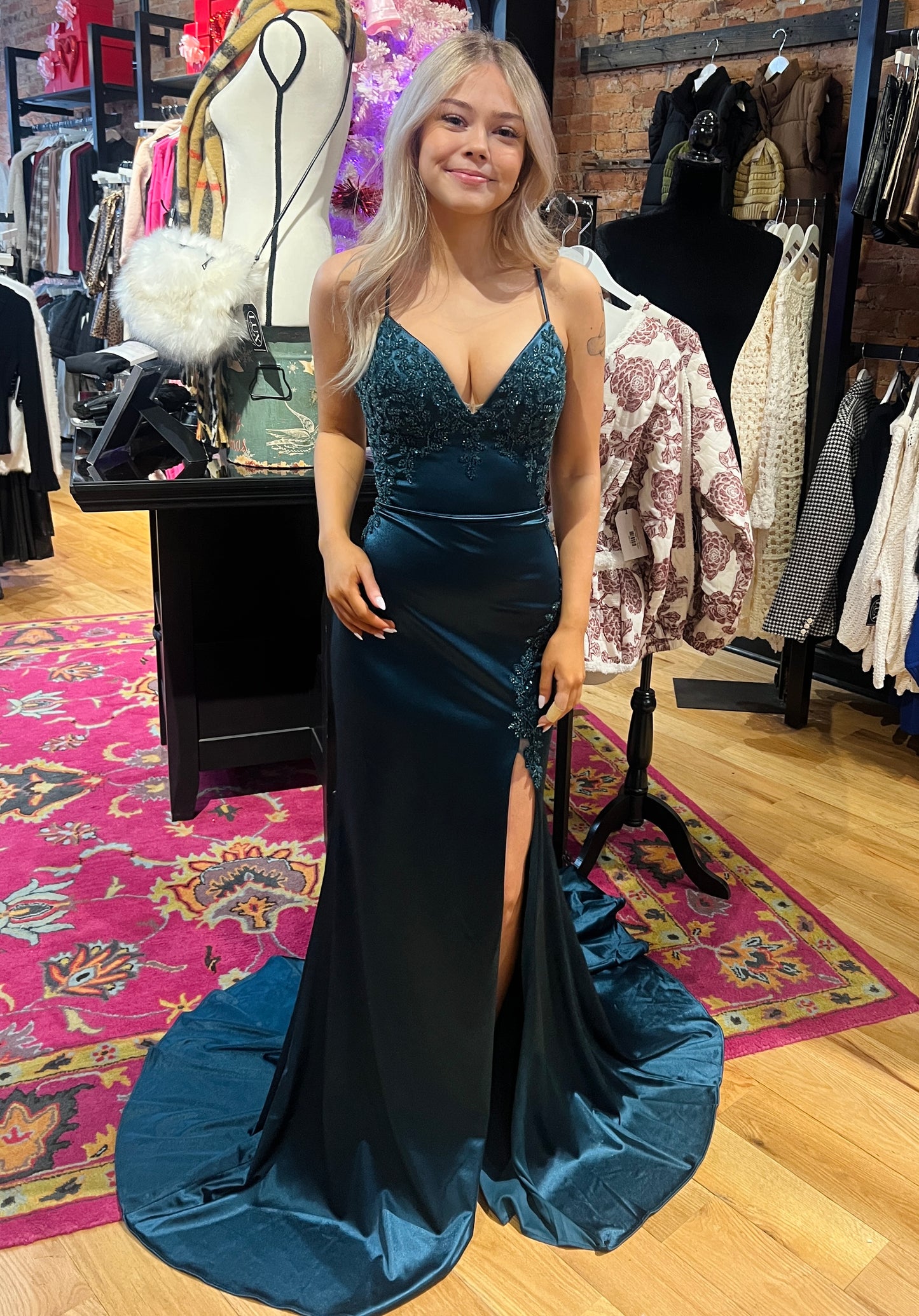 Woman in a blue evening gown standing in a clothing store.