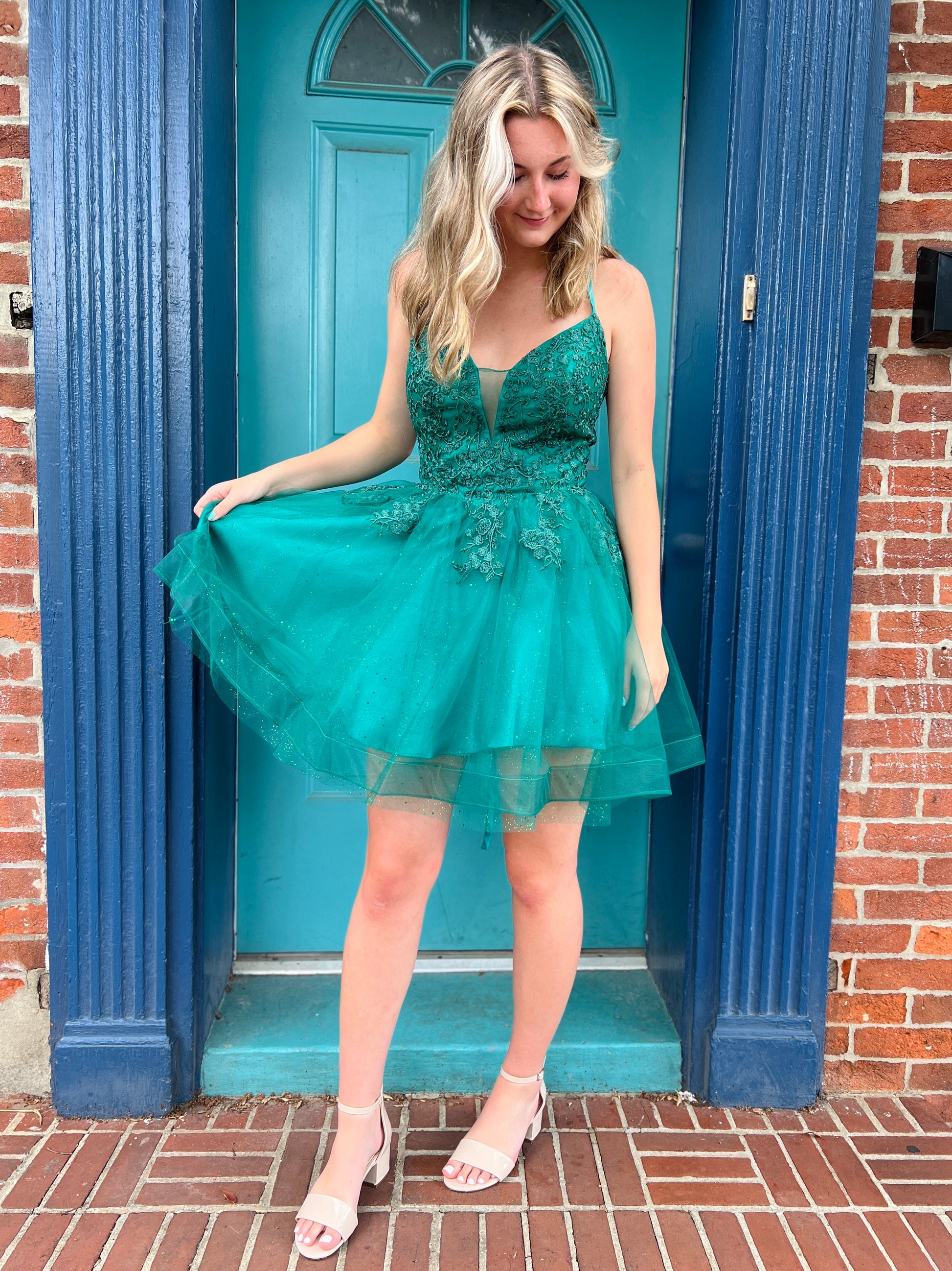 Woman in a teal dress standing in front of a blue door.