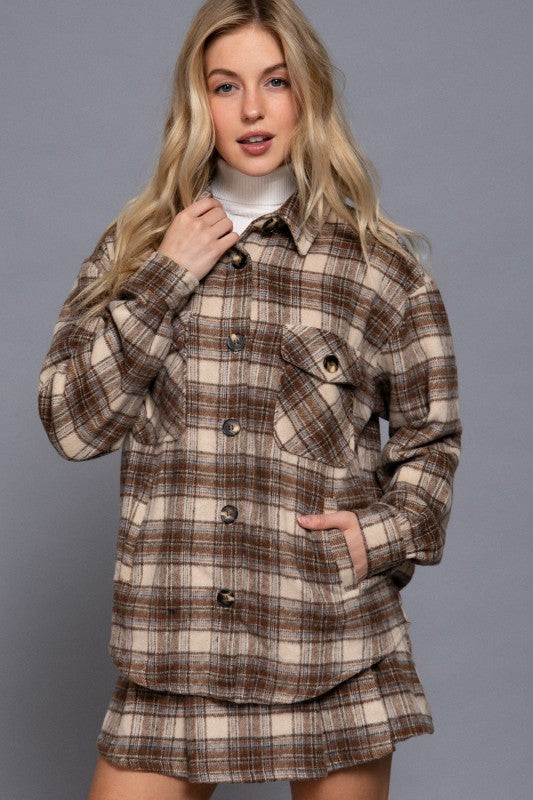 Woman wearing a plaid shirt over a white top against a gray background