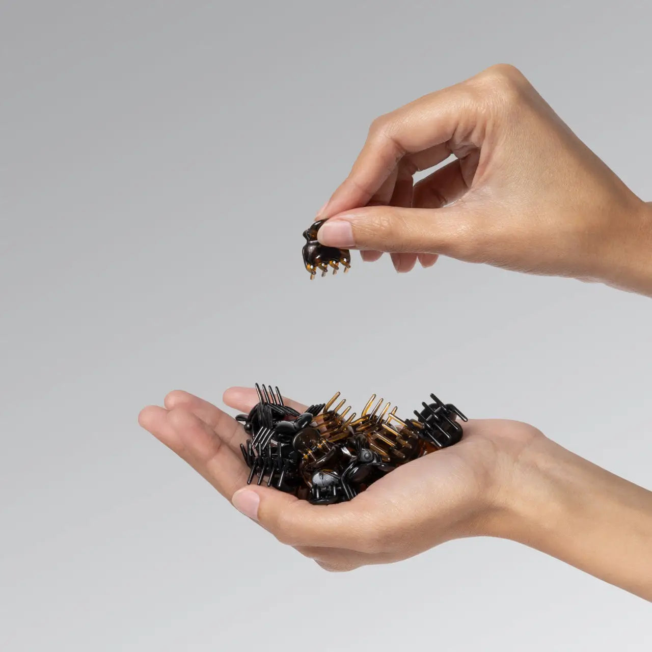 Hand holding a collection of hairbrushes against a gray background