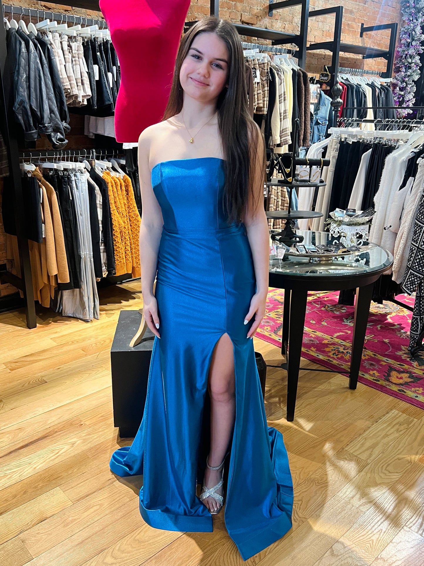 Woman in a blue strapless gown standing in a clothing store.