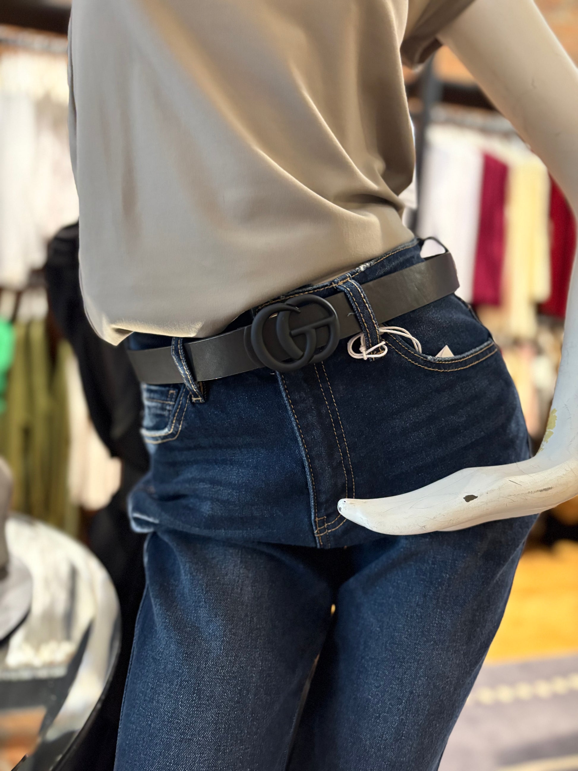 Person wearing a black belt with a large buckle, standing in an indoor setting.