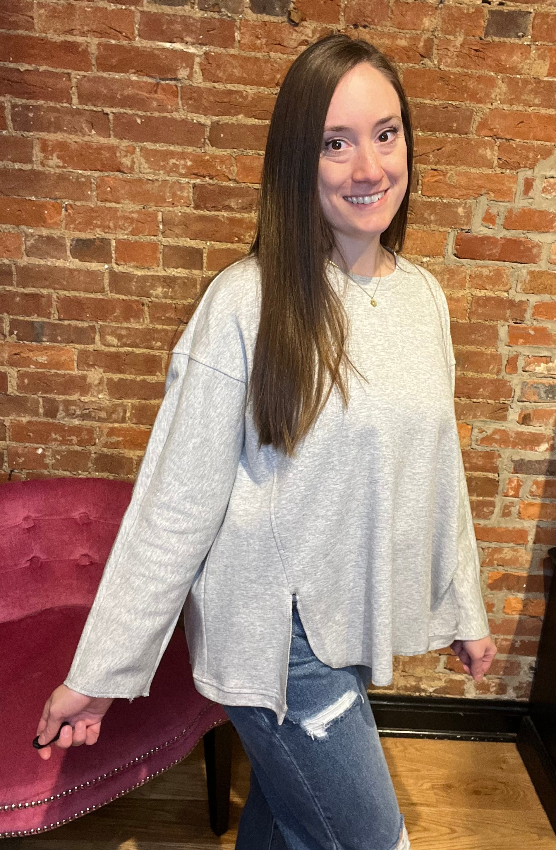 woman wearing a long sleeve grey-colored pull over sweater with denim jeans and boots