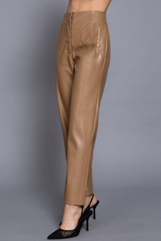 Tan leather pants worn by a person on a gray background