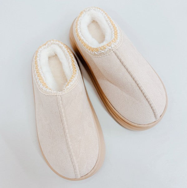 Pair of beige slippers on a light gray background