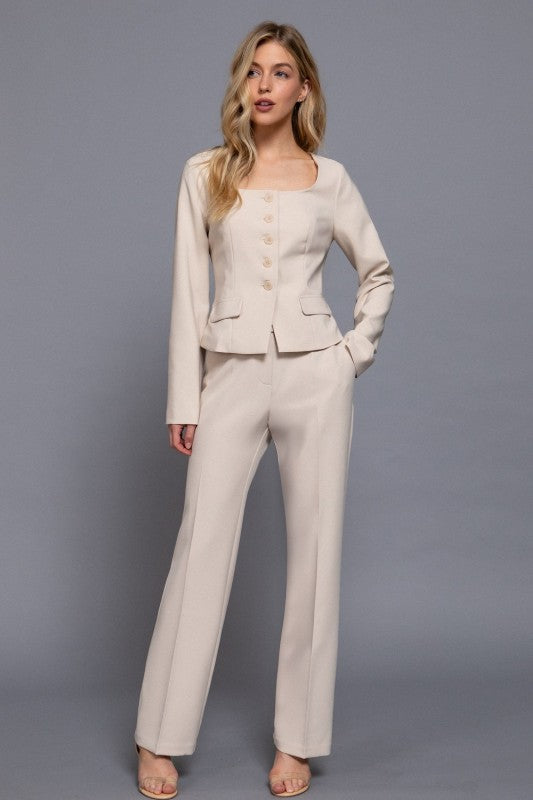 Woman wearing a beige suit against a gray background