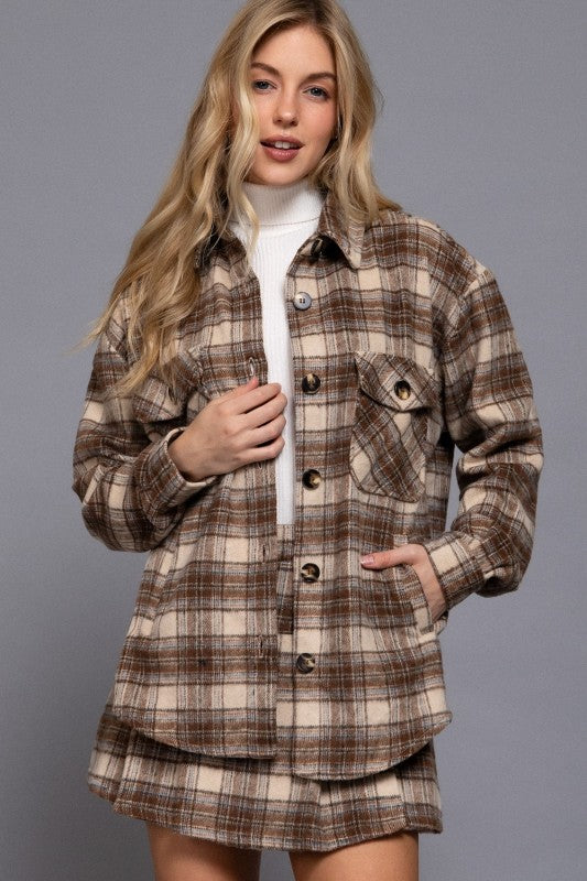 Woman wearing a plaid shirt over a white sweater on a gray background