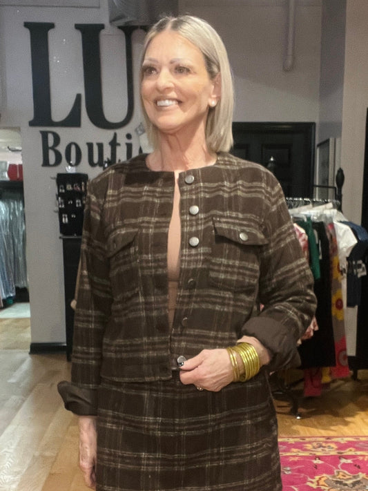 Woman wearing a plaid dress in a clothing store with 'Lush Boutique' sign.