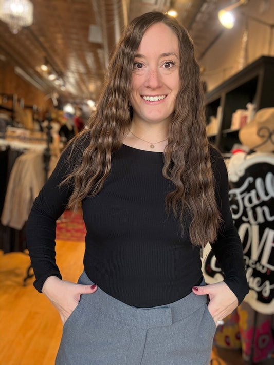 Woman wearing a black top and gray pants in a store setting