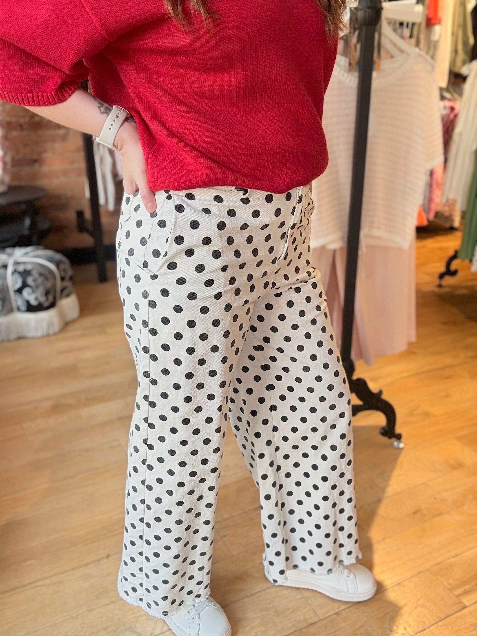 Person wearing a red sweater and polka dot pants in a store setting