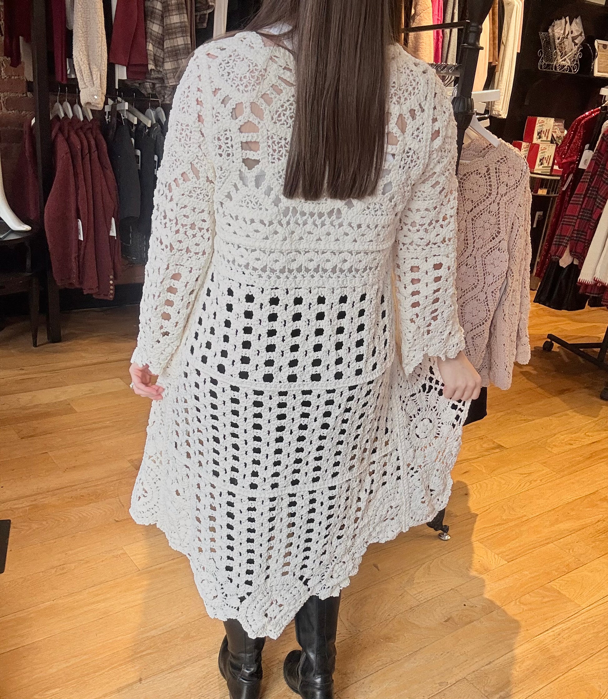 Person wearing a white crochet cardigan in a clothing store.