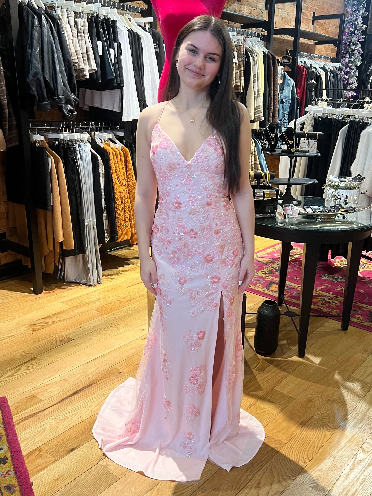 Woman in a pink floral dress standing in a clothing store.