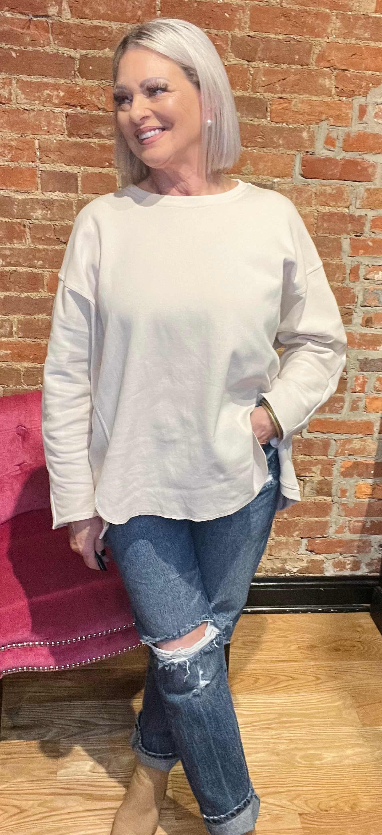 woman wearing a long sleeve cream-colored pull over sweater with denim jeans and boots