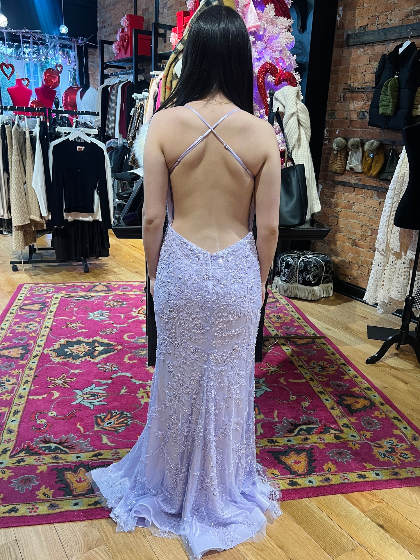 Woman wearing a sparkly silver dress with a backless design in a clothing store.
