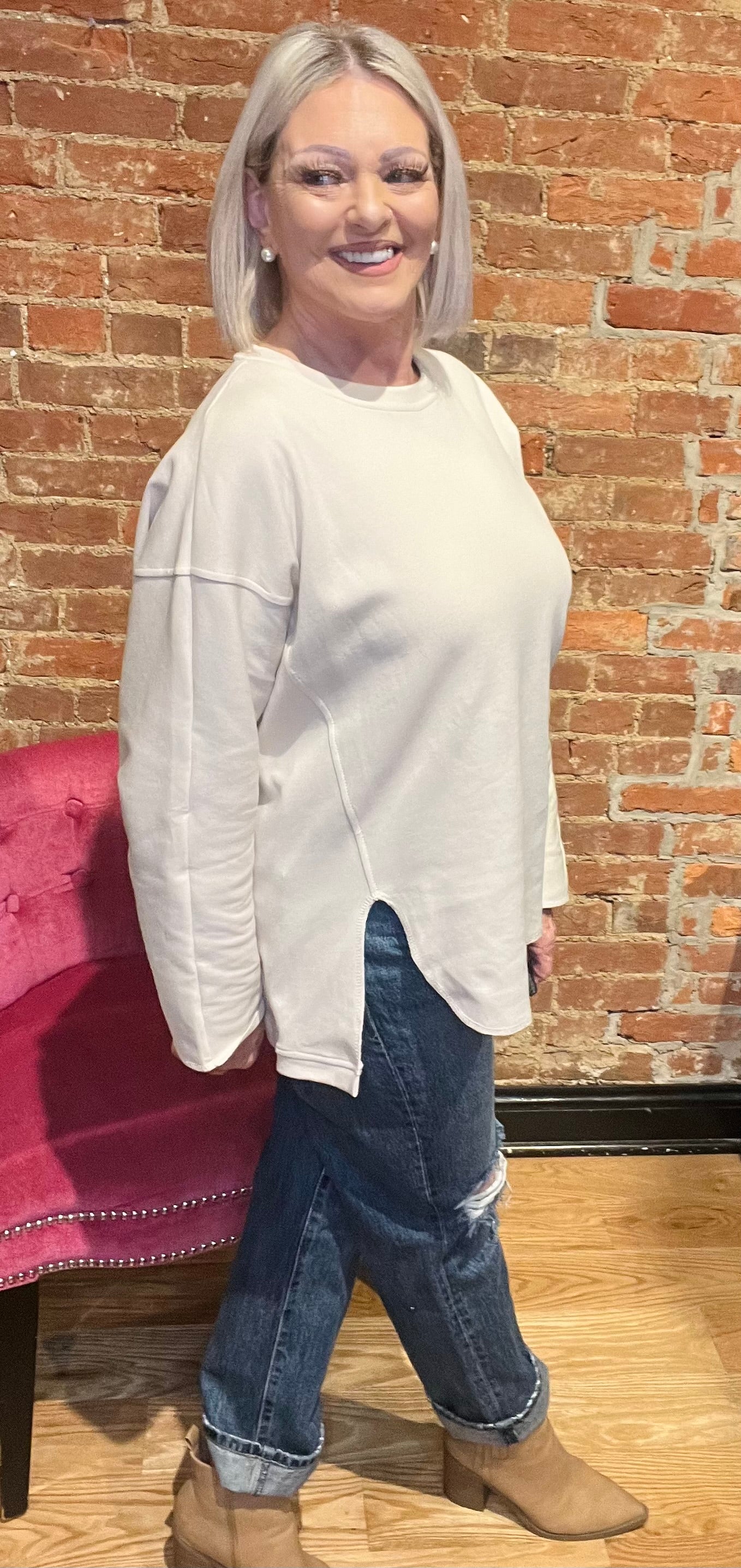 woman wearing a long sleeve cream-colored pull over sweater with denim jeans and boots