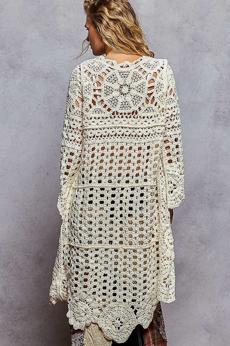 Woman wearing a crochet dress against a gray background