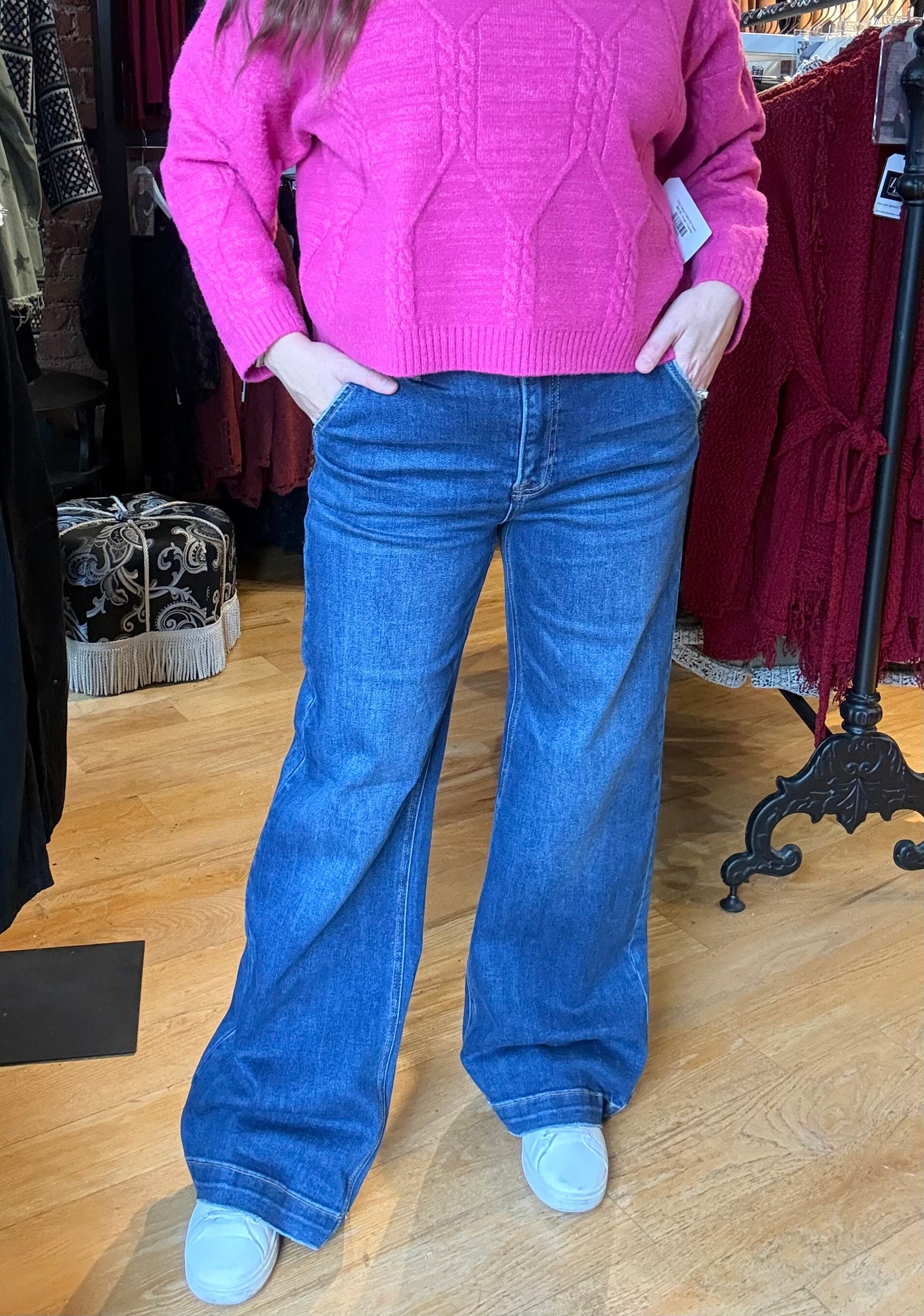 Person wearing a pink sweater and blue jeans in a clothing store.