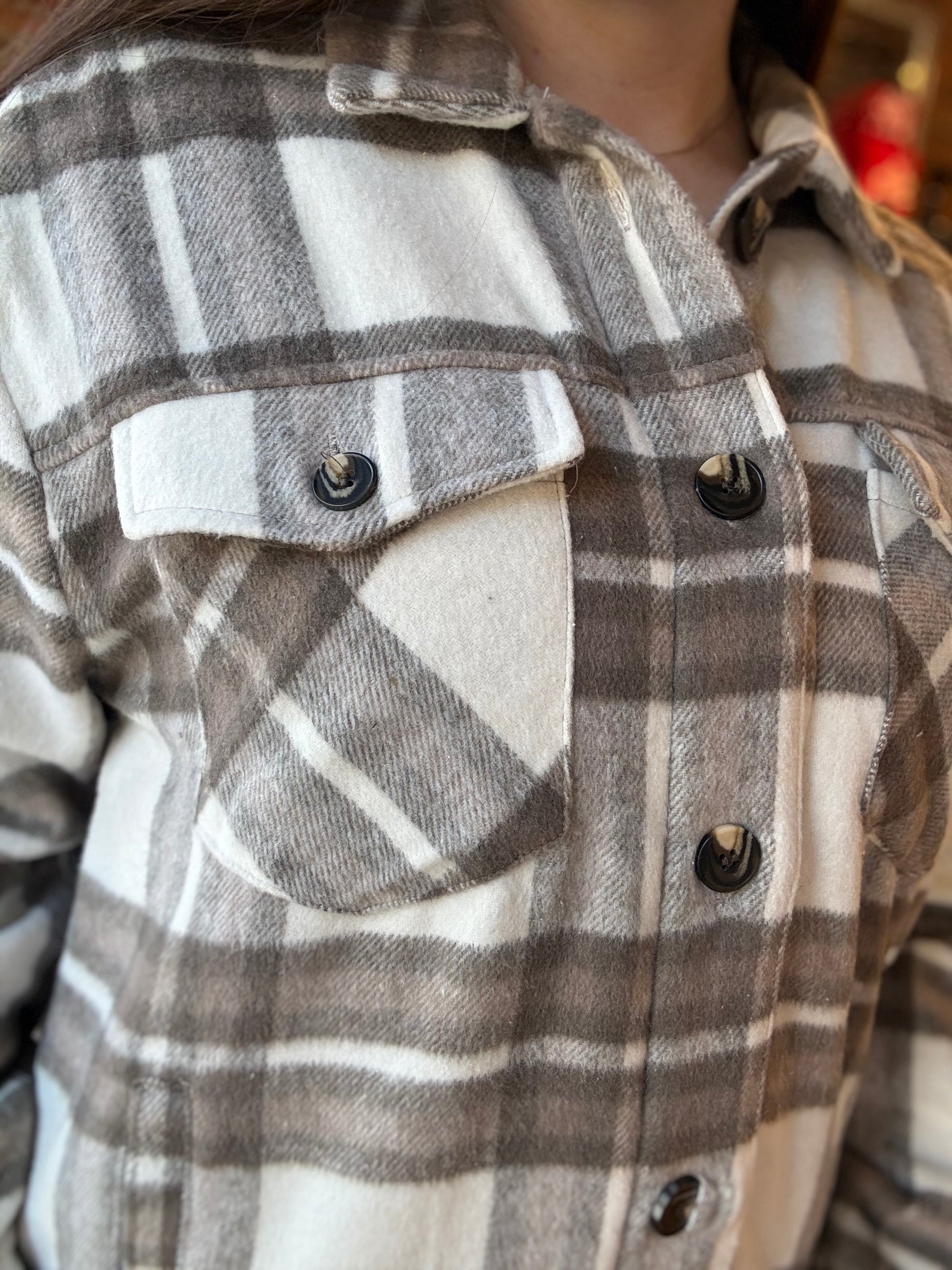 Close-up of a person wearing a plaid shirt with a neutral background