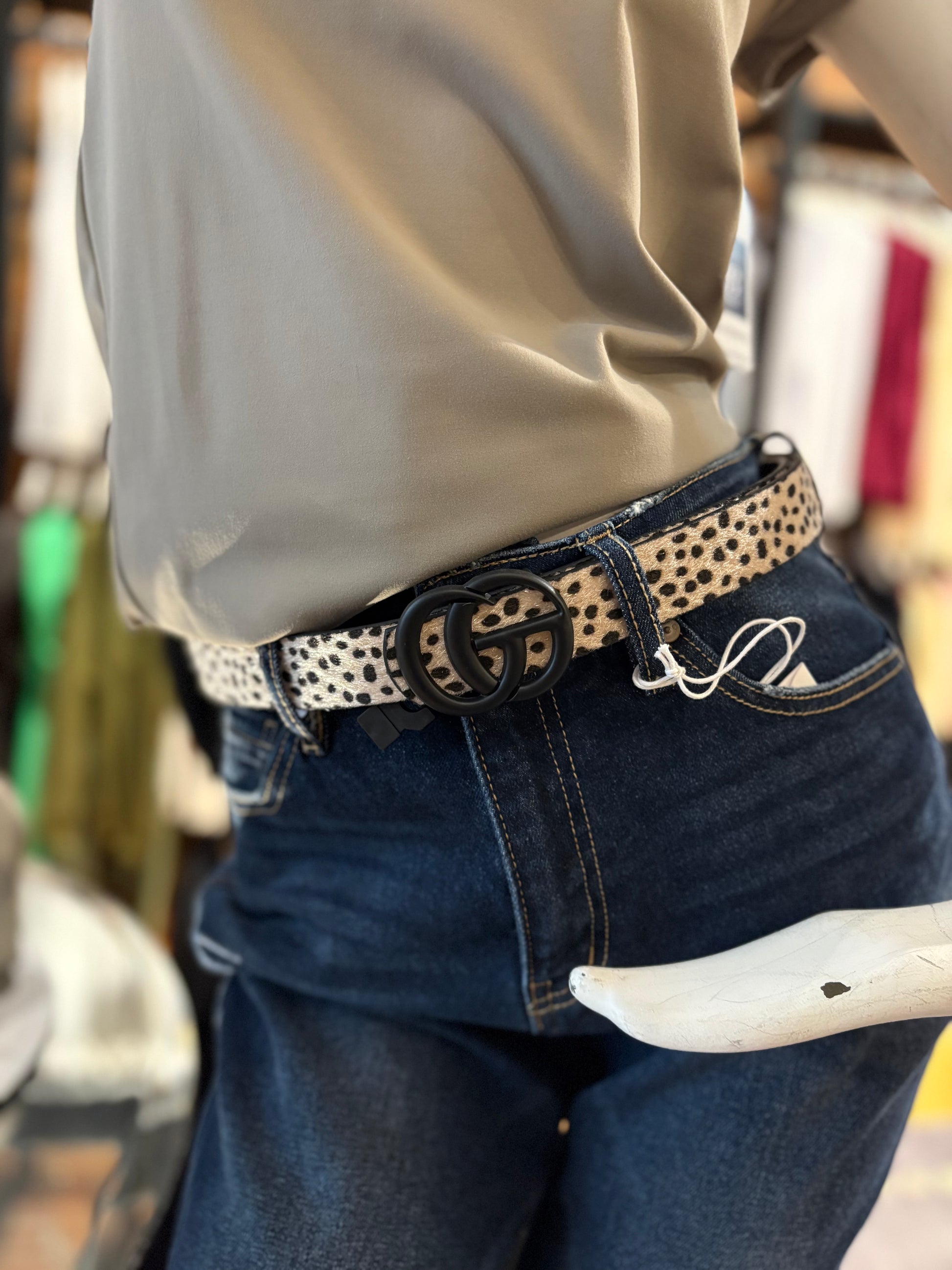 Person wearing a belt with a decorative buckle and jeans, blurred background