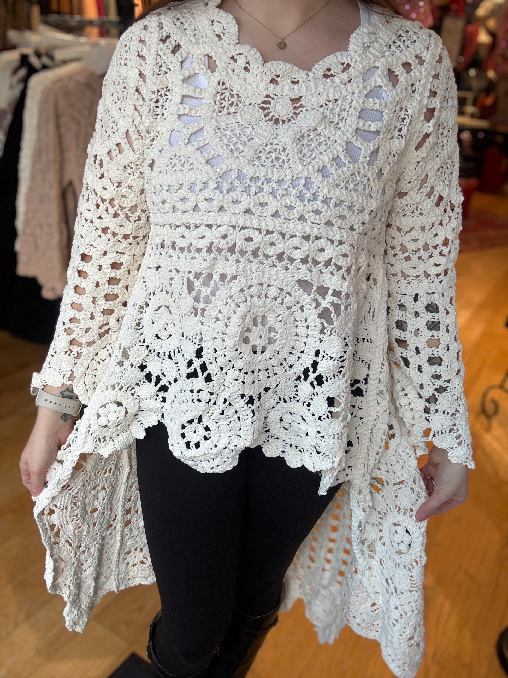 Person wearing a white crochet top with a blurred background