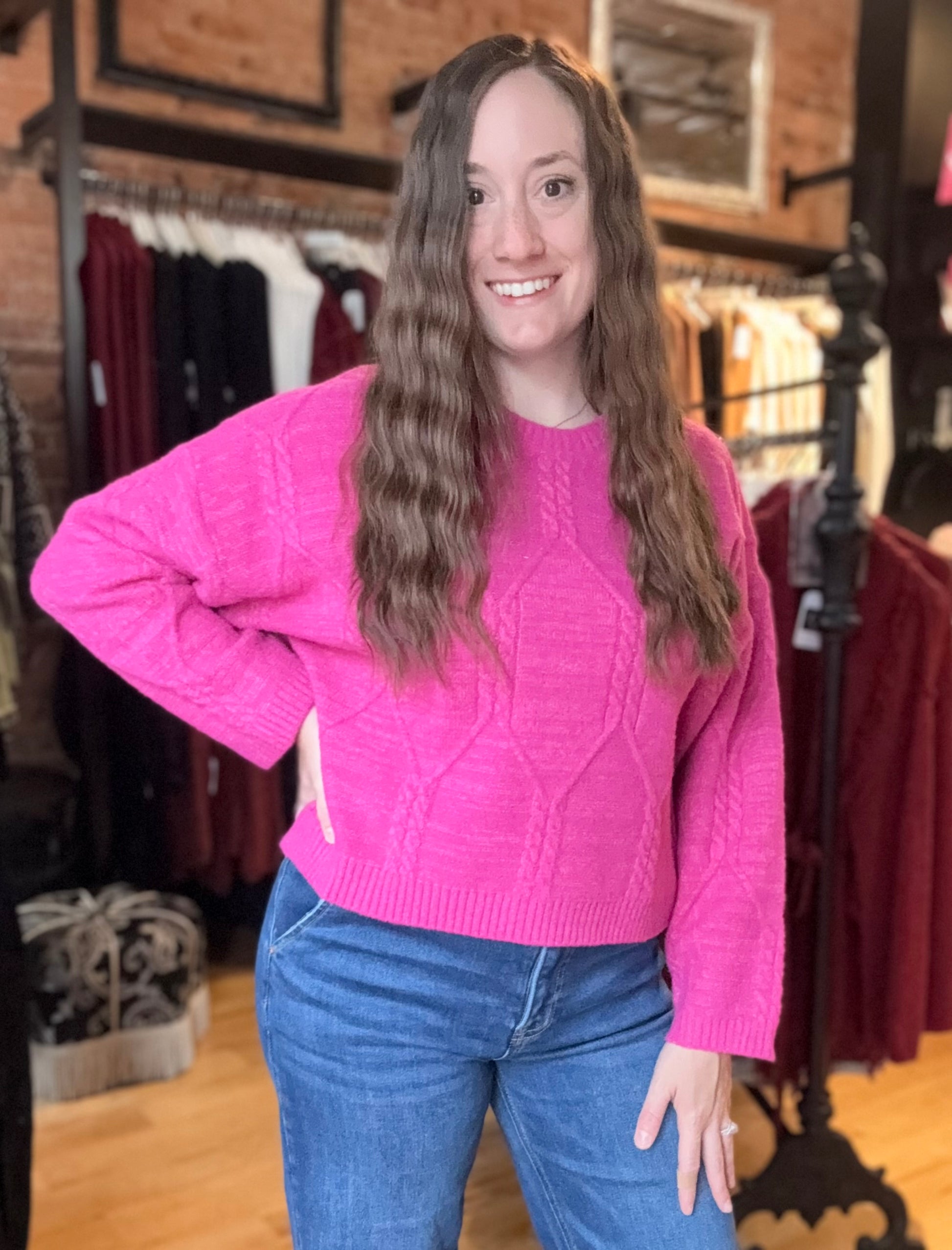 Person wearing a pink sweater and blue jeans in a clothing store.