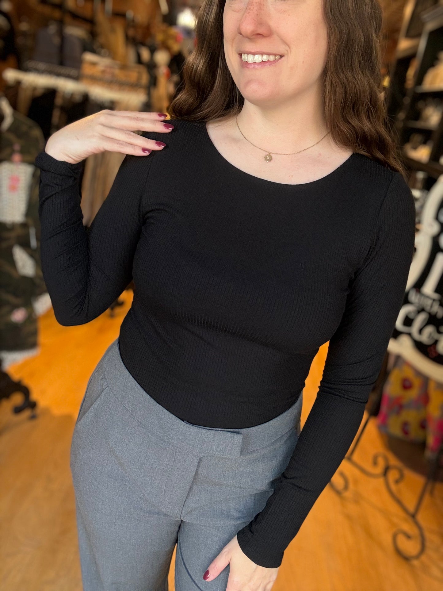 Woman wearing a black long-sleeve top and gray pants in a store setting
