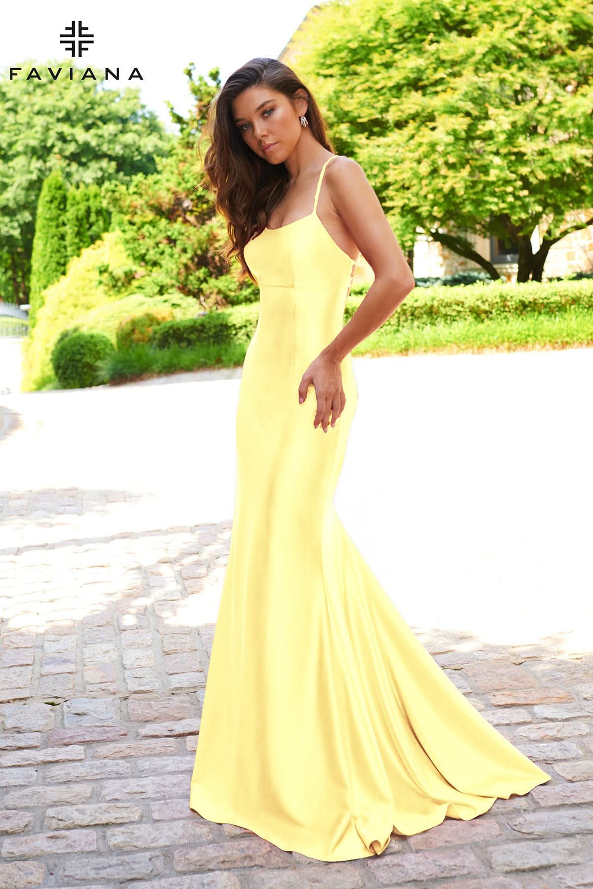 Woman in a yellow dress standing outdoors with 'Faviana' branding.
