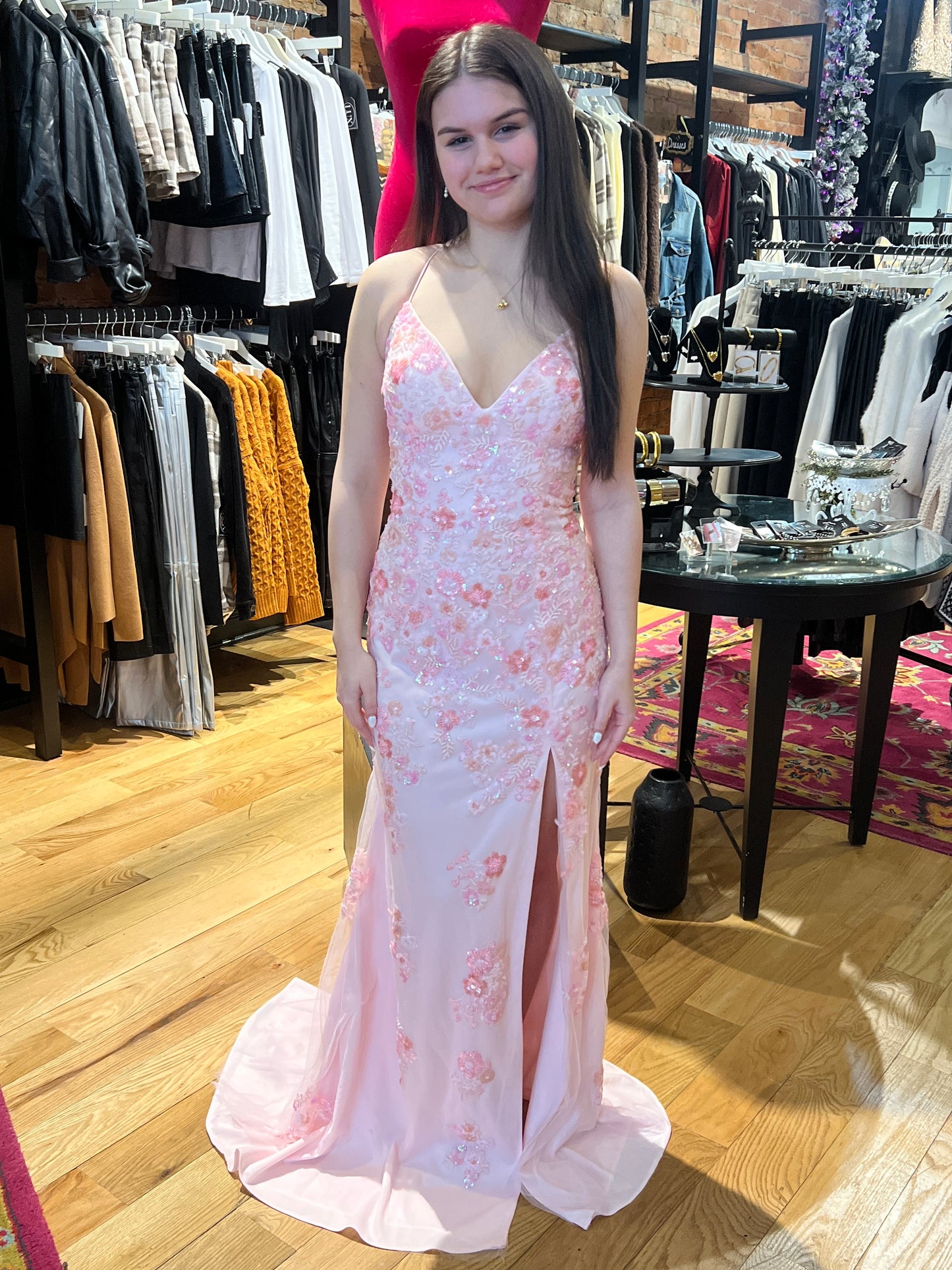 Woman in a floral evening gown standing in a clothing store.