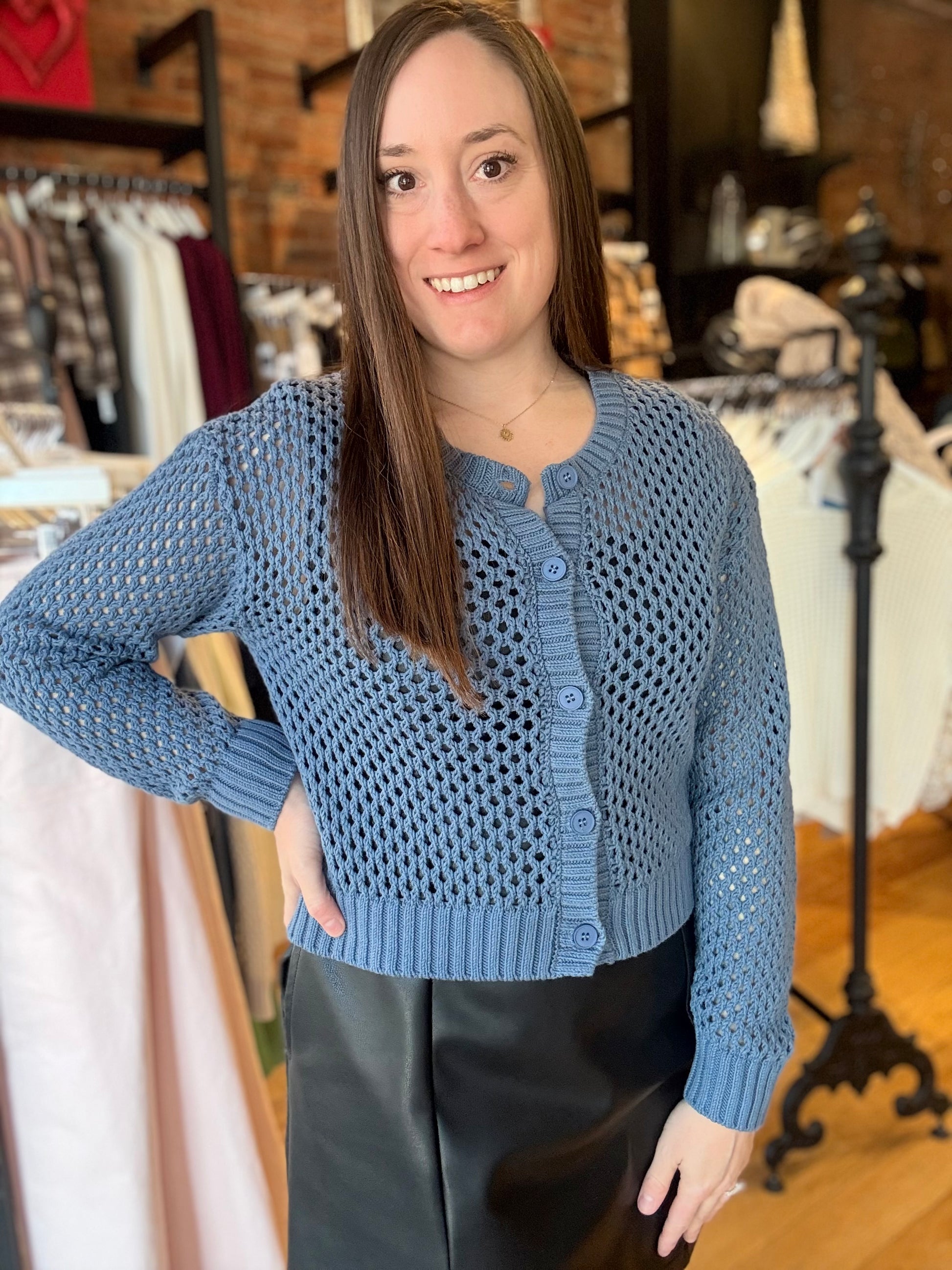 Woman wearing a blue knitted cardigan in a clothing store.