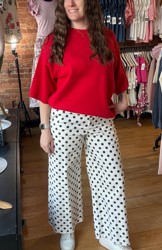 Person wearing a red top and polka dot pants in a clothing store.