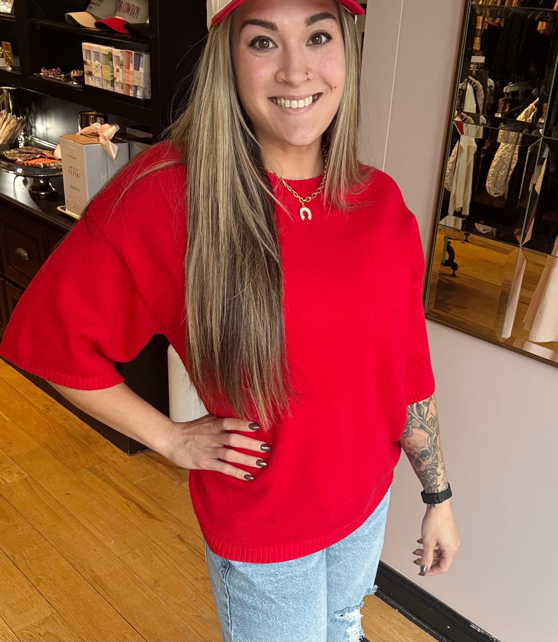 Woman wearing a red sweater and cap indoors, possibly in a store.