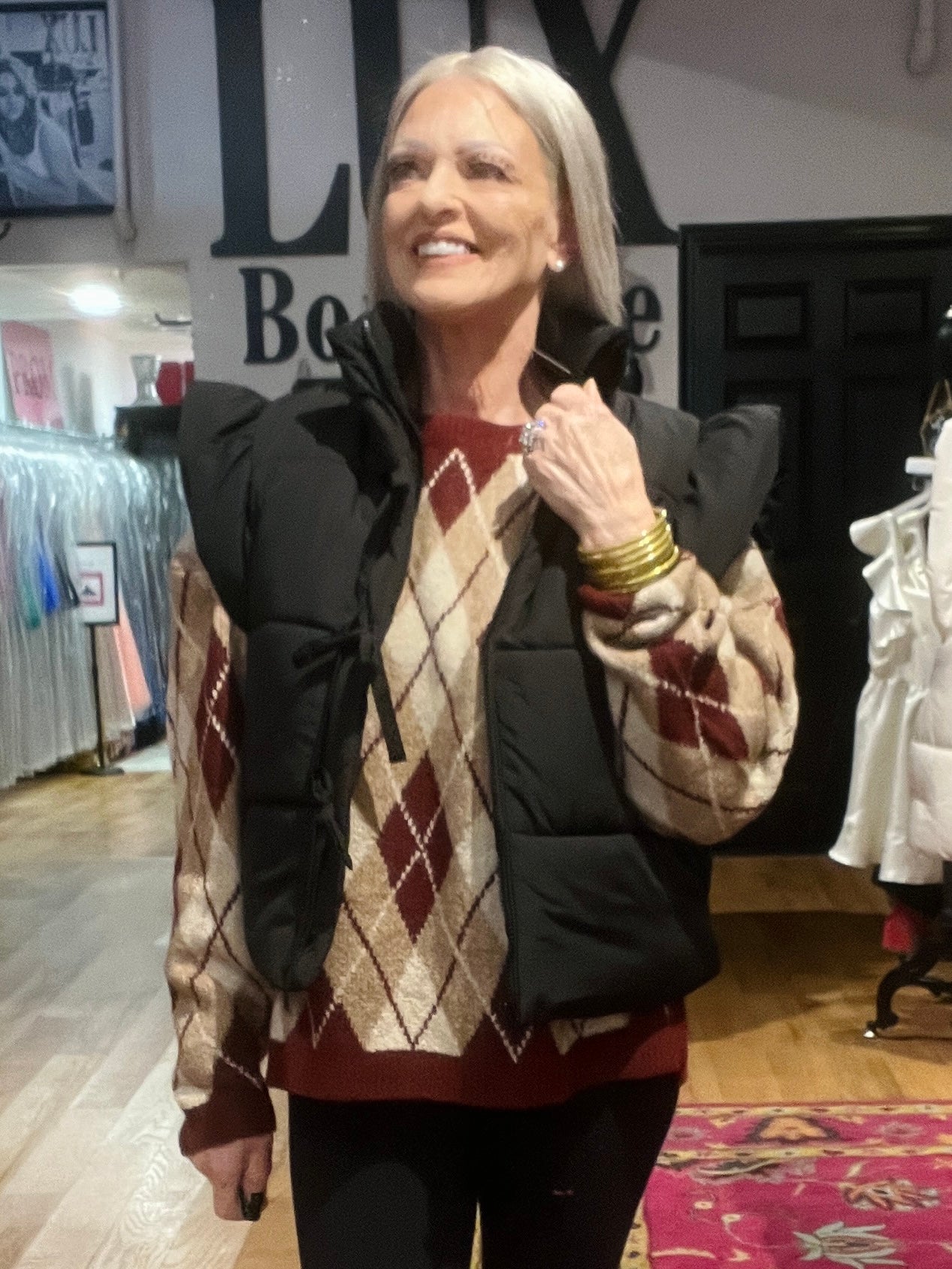 Woman wearing a patterned sweater and black jacket in an indoor setting