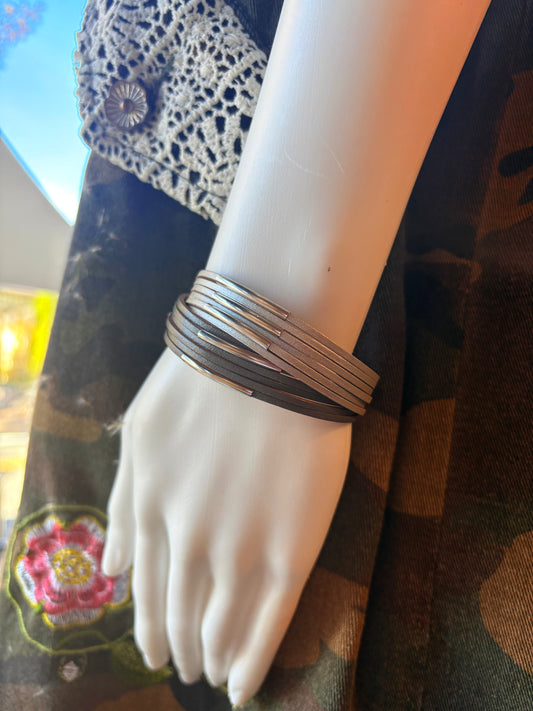 Mannequin arm wearing multiple bracelets on a patterned fabric background