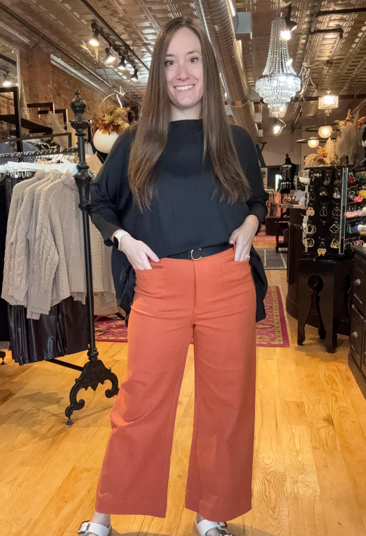 Woman wearing a black top and orange pants in a store setting
