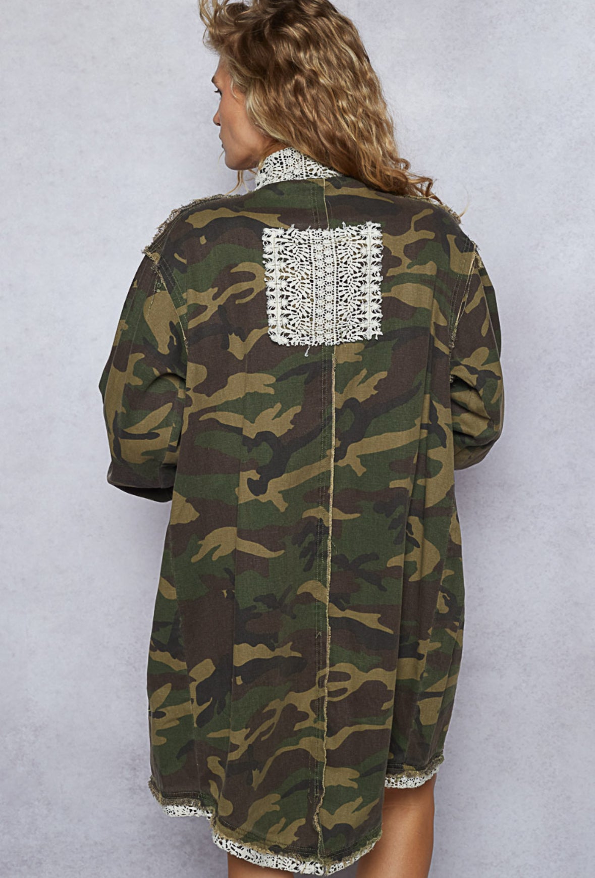 Camouflage jacket with lace details on a plain background