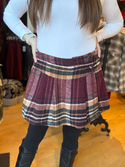 Person wearing a plaid skirt and black boots in a clothing store.