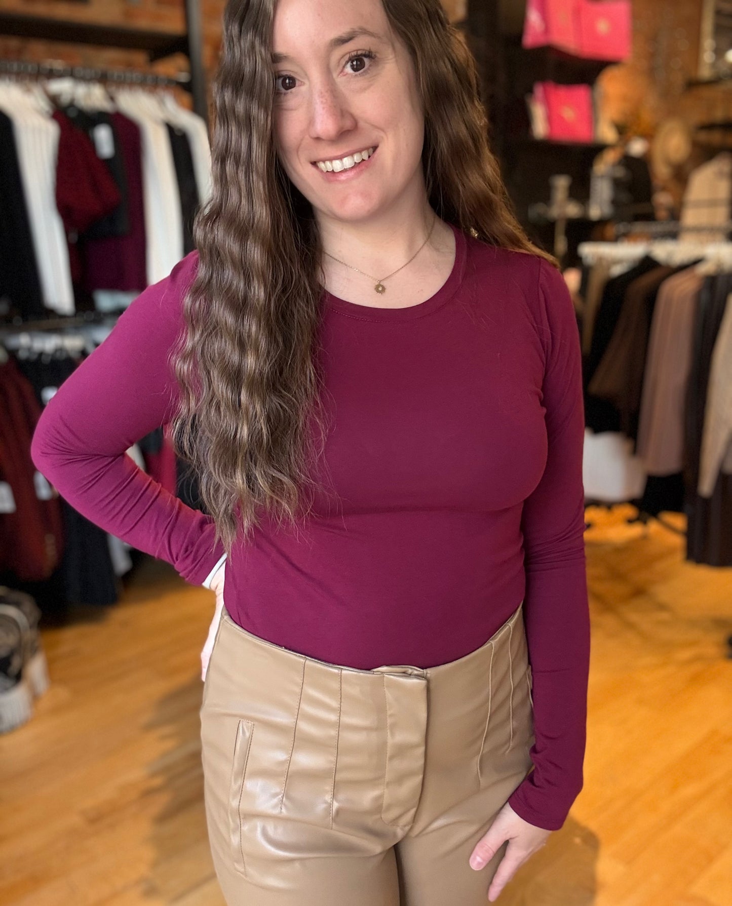 Woman wearing a maroon long-sleeve top and beige pants in a clothing store.
