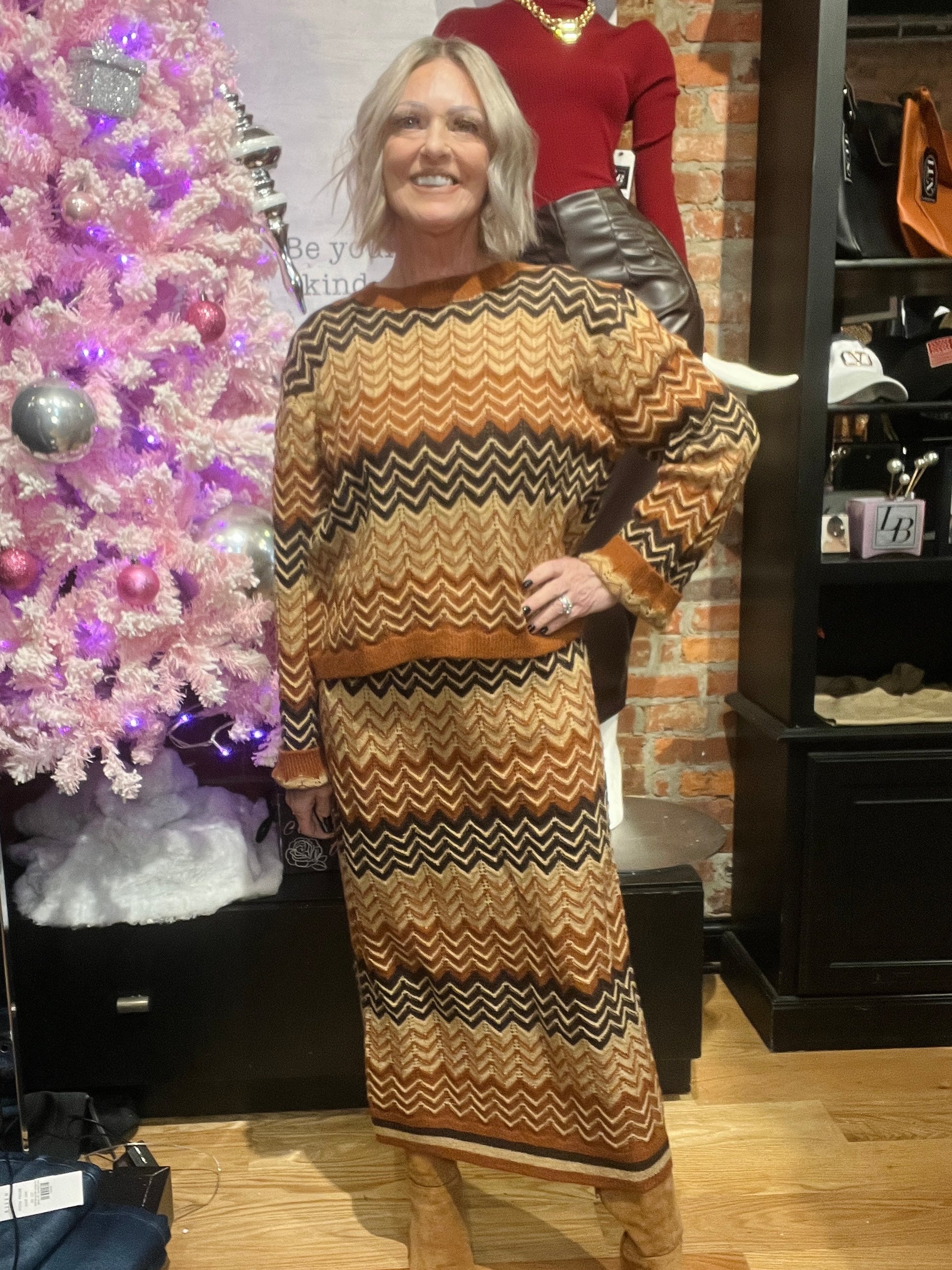 Woman wearing a patterned dress standing in front of a decorated Christmas tree and store display.