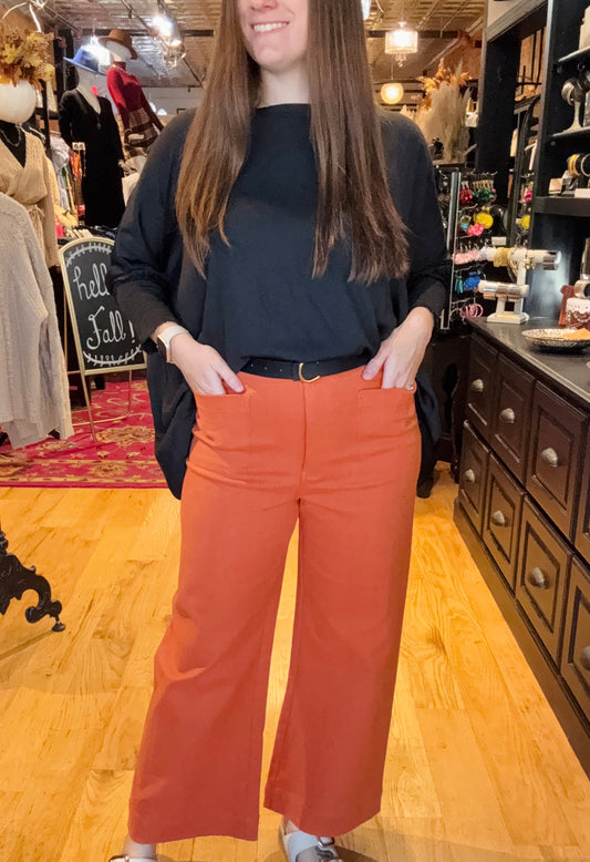 Person wearing a black top and orange pants in a store setting