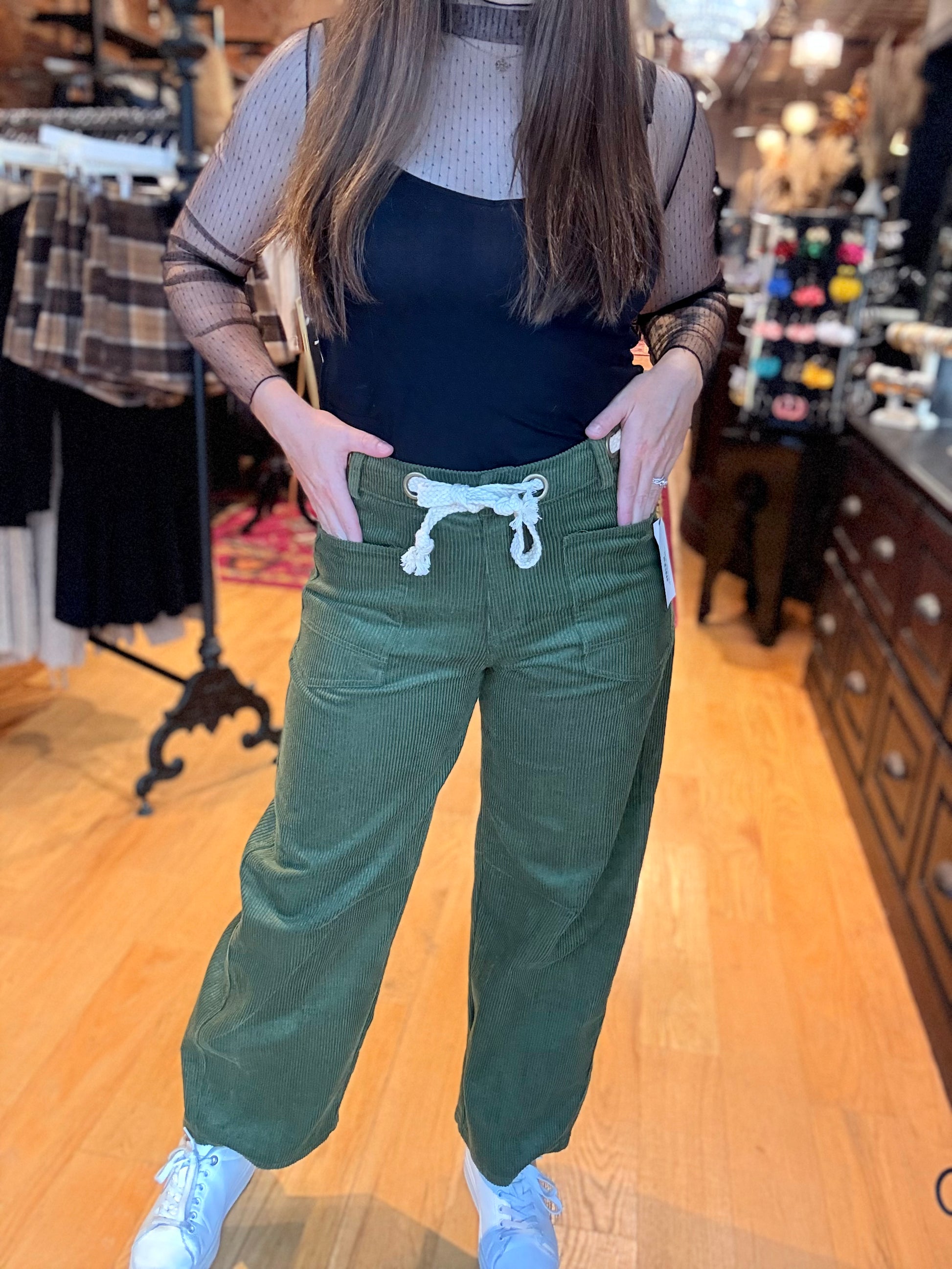 Person wearing green pants with a drawstring in a store setting